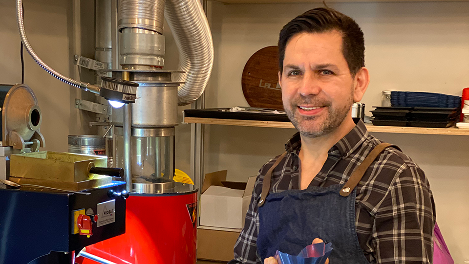 Fulcrum Coffee Head Roaster and Senior Vice President Blas Alfaro standing in front of a coffee roasting machine.