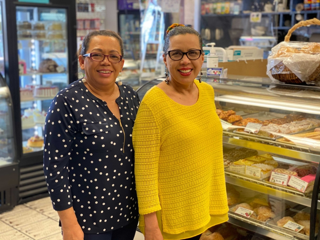 Sisters Aminta Elgin and Ana Castro standing in front of one of their pastry cases.