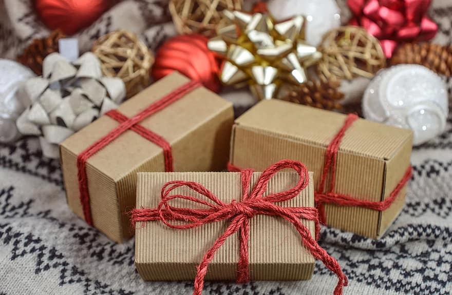 Brown packages tied with red string on a blanket with star-shaped bows in the background.
